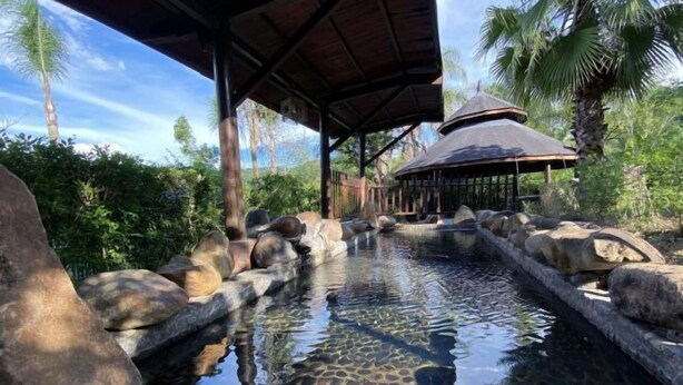 Un espace piscine extérieur paisible, agrémenté d’un gazebo en bois, entouré de rochers et d’une végétation luxuriante.