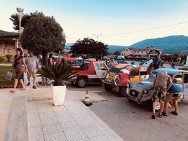 Una calle con vehículos estacionados y un hotel al fondo.