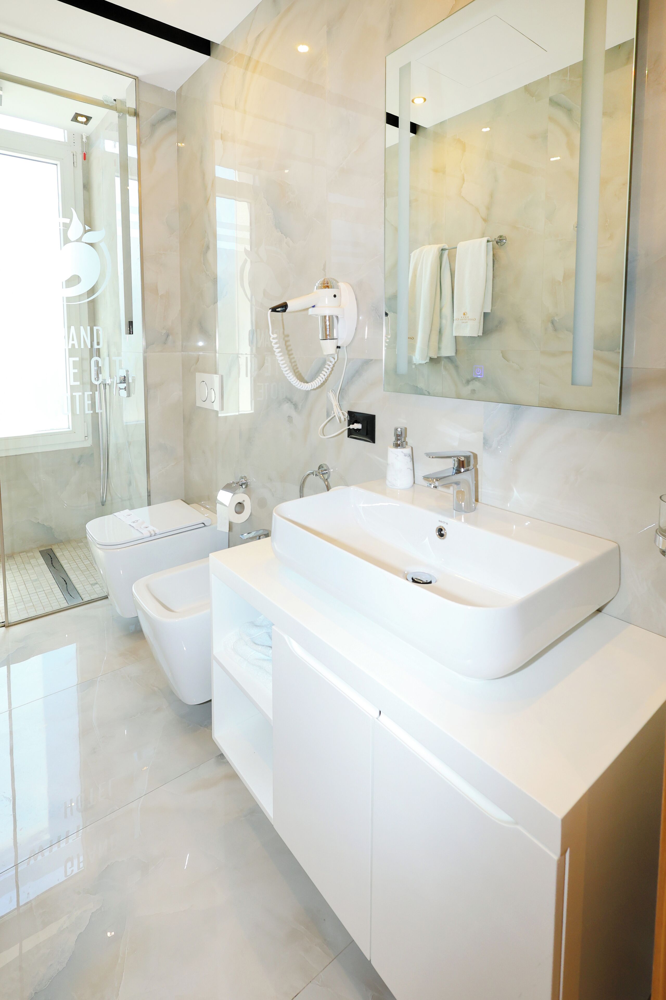 A modern bathroom with a large sink, a toilet, and a glass shower enclosure.