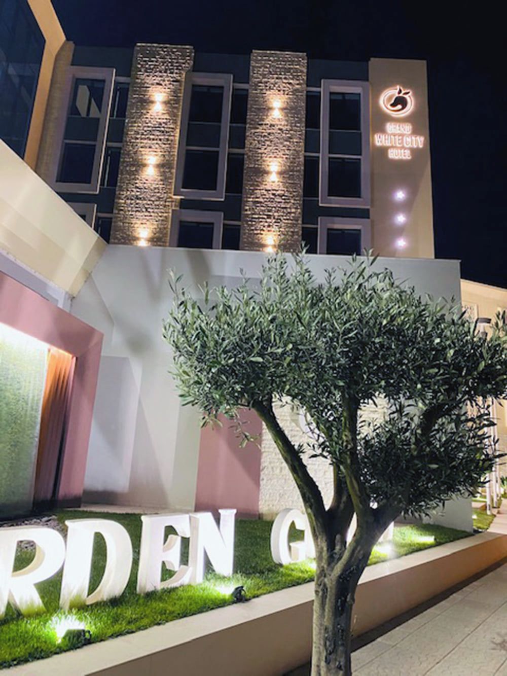 Un edificio moderno con columnas verticales iluminadas y un letrero que dice 