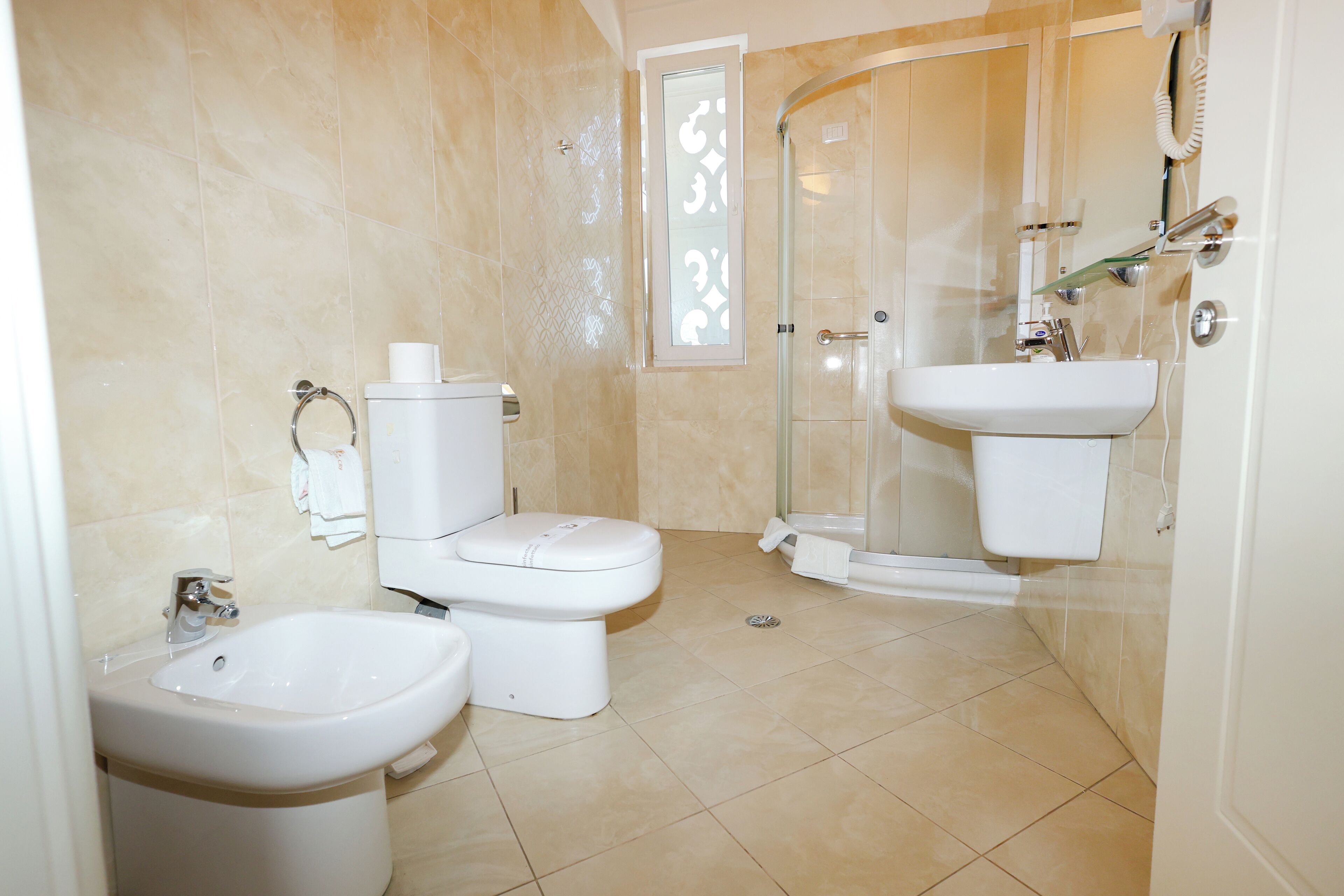 Un baño moderno con inodoro, bidé, lavabo y cabina de ducha de vidrio.
