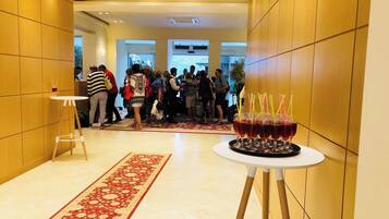 A hotel lobby with a patterned carpet, a reception area, and a buffet table with drinks.