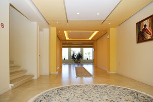 A spacious hallway with a patterned rug, a staircase, and a painting on the wall.