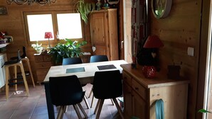 Ein Holzinnenraum mit einem Esstisch, Stühlen, einem Schrank und einem Fenster.