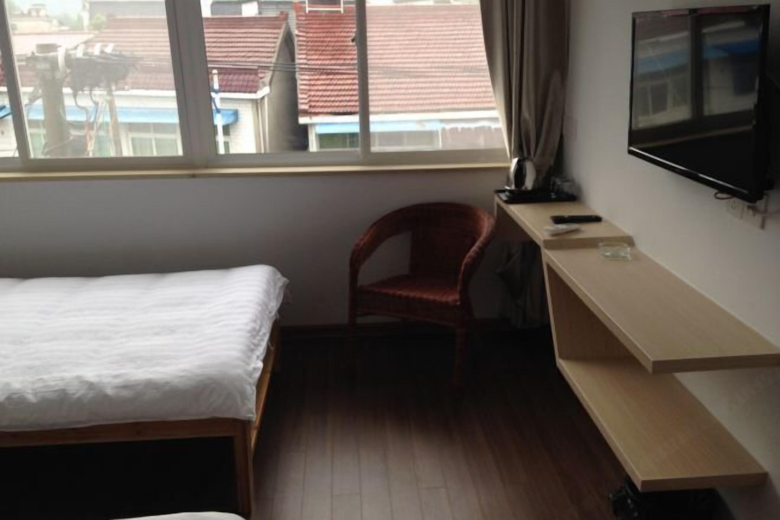 A bedroom with a bed, a chair, a TV, and a shelf.