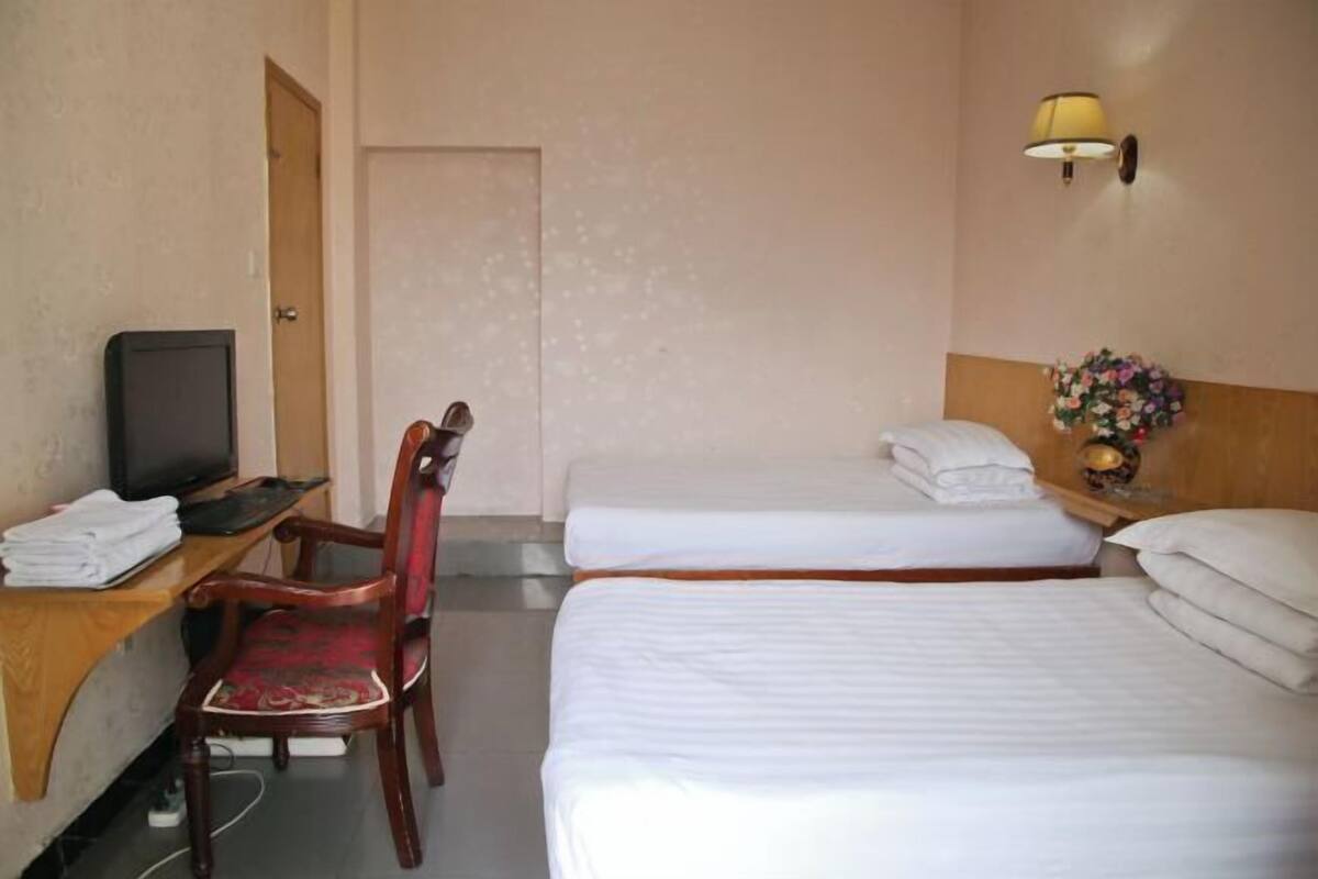 A hotel room with two beds, a desk with a computer, a chair, and a TV.
