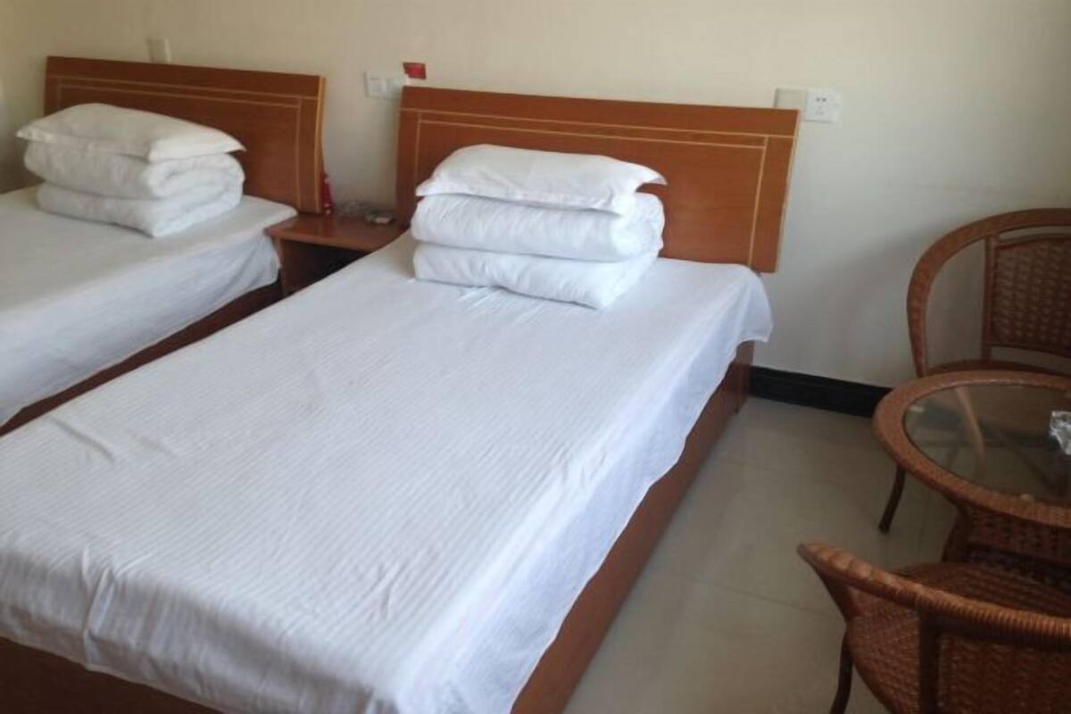 Two single beds with wooden headboards, a glass table, and wicker chairs.