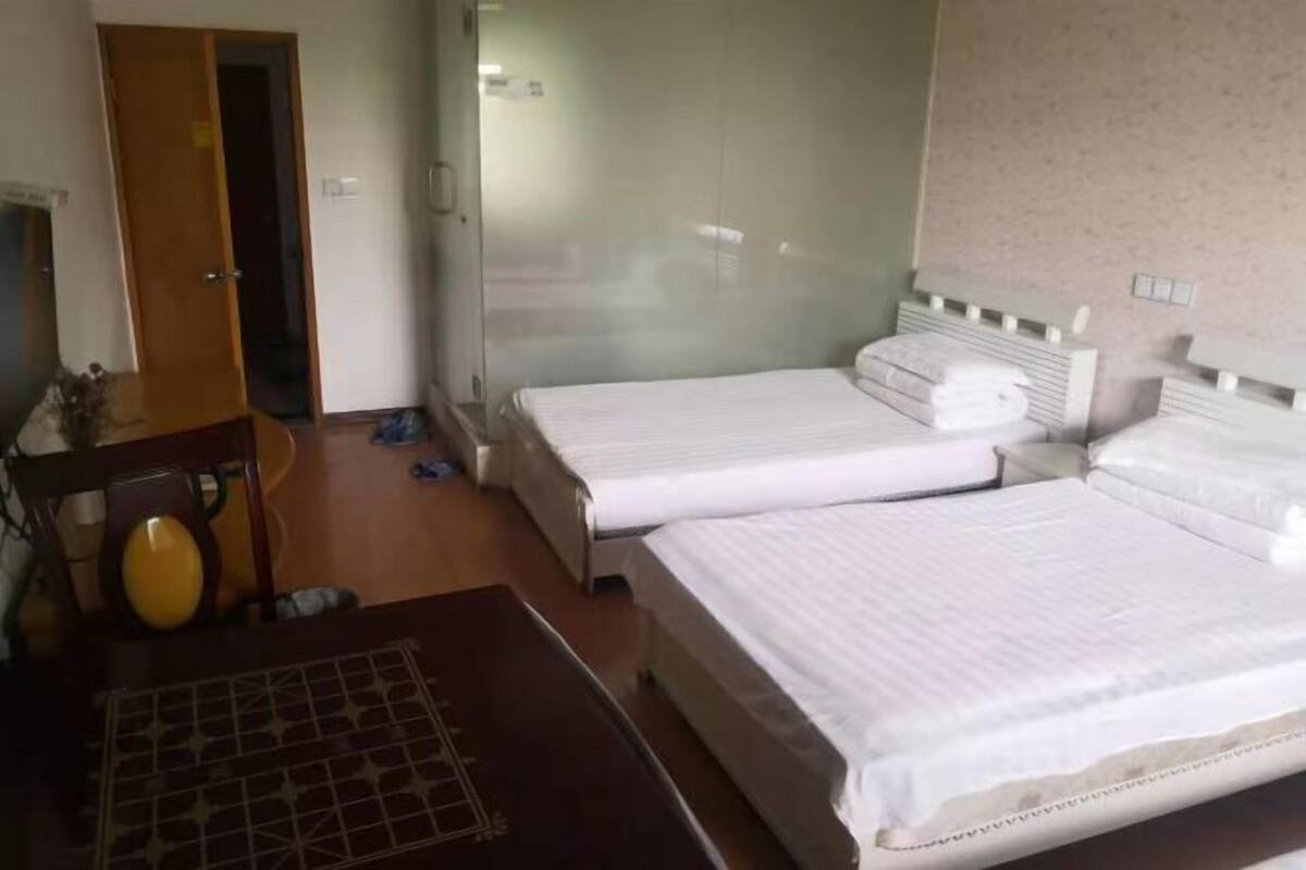 A room with two beds, a wooden table, and a chair.