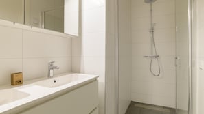 A modern bathroom with a shower, a sink, and a mirror.