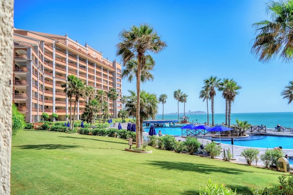 Un hôtel doté d’une piscine, de palmiers et offrant une vue sur l’océan.