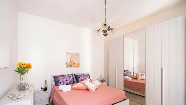 Une chambre à coucher comprenant un lit, des tables de chevet, une commode, un miroir et une armoire.