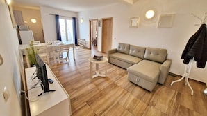 Ein modernes Wohnzimmer mit einer Couch, einem Essbereich und einem Fernseher.