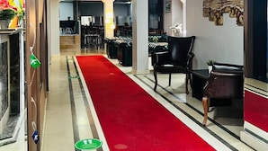 A hotel lobby with a red carpet, leather chairs, a reception desk, and a painting on the wall. - Lal Hotel (Istanbul)