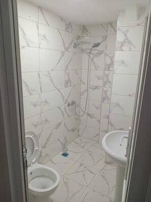 A bathroom with white marble tiles, a shower, and two sinks. - Lal Hotel (Istanbul)
