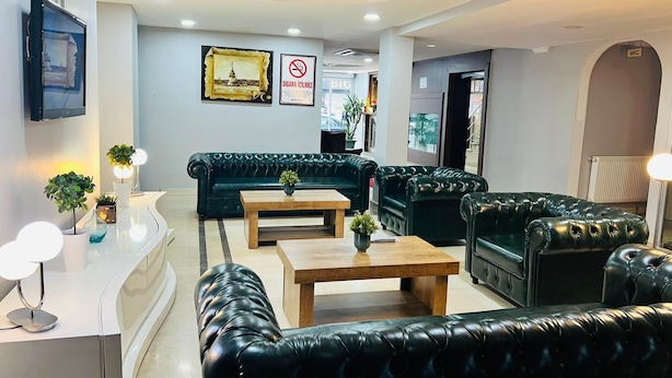 A modern hotel lobby with leather sofas, a wooden coffee table, and a chandelier. - Lal Hotel (Istanbul)