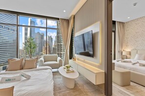 Quarto de hotel moderno com televisão grande, assentos confortáveis, vista para a cidade e um minibar.