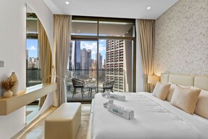 Quarto de hotel com uma cama grande, escrivaninha, cadeira e varanda com vista para a cidade.