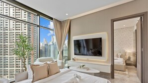 Een moderne hotelkamer met een groot bed, een televisie, een zithoek en uitzicht op de stad.