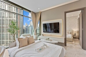 Una habitación de hotel moderna con una cama grande, un televisor, un área de descanso y vistas a la ciudad.