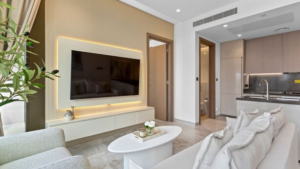 Een moderne woonkamer met een grote flatscreen televisie, een witte bank en een salontafel.