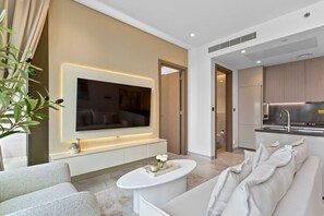 Una sala de estar moderna con un televisor de pantalla plana grande, un sofá blanco y una mesa de centro.