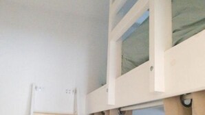 Una cama litera con escalera, cortinas color beige y una ventana.