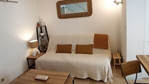 Un dormitorio con cama, mesitas de noche, un espejo y una pequeña mesa con una silla.