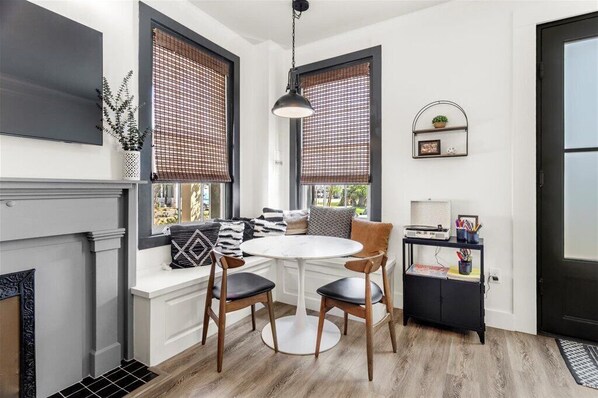 Una cocina moderna con una mesa de comedor redonda, dos sillas de madera, un armario negro y una ventana con marco negro que ofrece vistas.