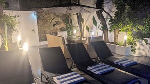 Un espace de détente extérieur, baigné de lumière, avec trois chaises longues, chacune agrémentée d’une serviette à rayures.