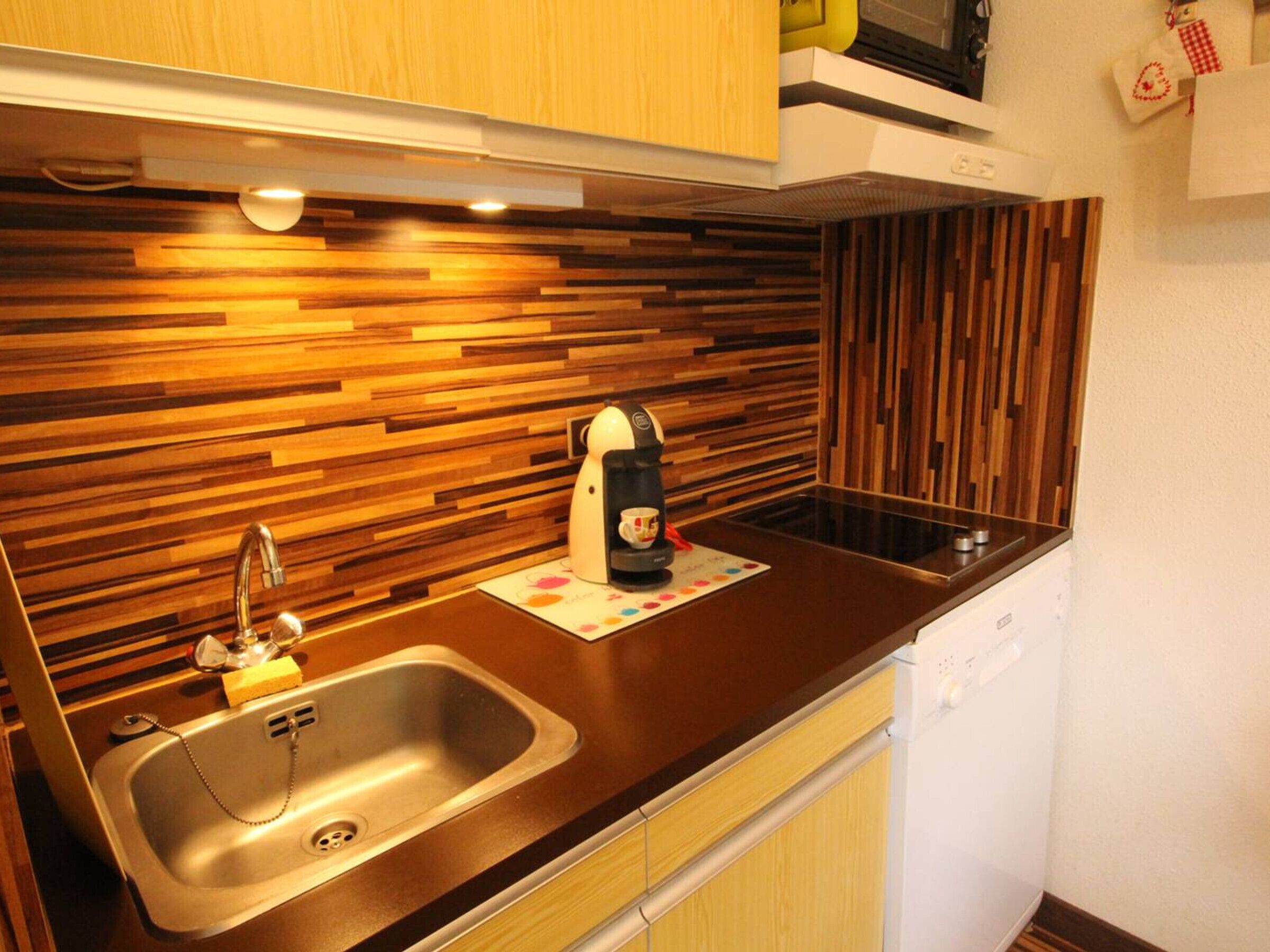 Una cucina moderna con schienale in legno, lavello in acciaio inossidabile e macchina per il caffè.