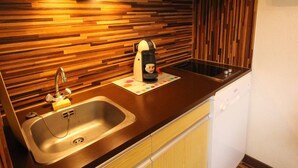 A modern kitchen with a wooden backsplash, stainless steel sink, and a coffee machine. - Luchon - Studio 2/3 pers., balcony, cable car, near shops and thermal baths (Bagnères-de-Luchon)