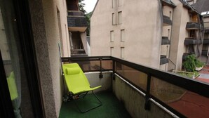 A balcony with a green artificial turf floor, a single bright green chair, and a glass door leading to an interior space. - Luchon - Studio 2/3 pers., balcony, cable car, near shops and thermal baths (Bagnères-de-Luchon)