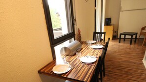 A dining area with a wooden table set for two, a sofa, and a television in the background. - Luchon - Studio 2/3 pers., balcony, cable car, near shops and thermal baths (Bagnères-de-Luchon)