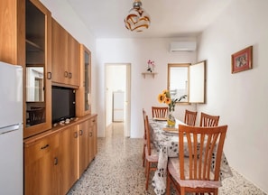 Une cuisine compacte avec des meubles en bois, une cuisinière encastrée et un coin repas avec une table dressée pour quatre personnes.