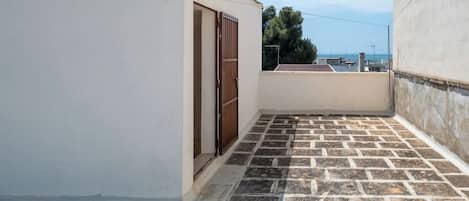 A rooftop with a paved floor, a door, and a view of the cityscape.