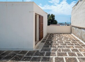 A rooftop with a paved floor, a door, and a view of the cityscape.