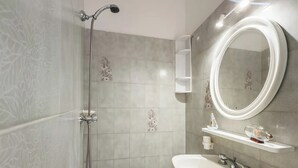 Een moderne badkamer met douche, toilet en wastafel.