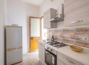 A modern kitchen with a built-in gas stove, a refrigerator, and a wooden backsplash.
