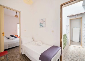 A bedroom with a bed, a small table, a chair, a door leading to another room, and a wall-mounted light fixture. - Mare e Frescura Sea View (Porto Cesareo)
