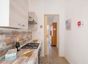 Une cuisine moderne avec un revêtement mural imitant le bois, une cuisinière à gaz et un plan de travail agrémenté d’un plat décoratif en forme de feuille.