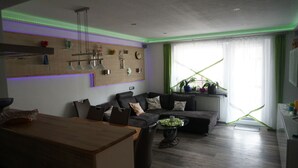 Ein modernes Wohnzimmer mit einem dunklen Sofa, einem Holzesstisch und einer grünen Pflanze.
