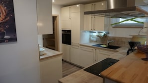 Eine moderne Küche mit weißen Schränken, einem schwarzen Backofen, einer Edelstahl-Dunstabzugshaube und einer Holz Arbeitsplatte.