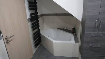Ein Badezimmer mit einer Badewanne, einem Handtuchhalter und einem Schrank.