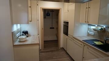 Une cuisine de taille réduite, avec des meubles de rangement en bois, un grille-pain, un panier et un évier.