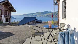 A patio area with a table and chairs, overlooking a lake and hills.