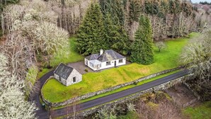 A stone house with a white exterior, surrounded by a green lawn and a stone wall. - Beautiful private villa for 8 guests with WIFI, TV, patio and panoramic view (Invermoriston)