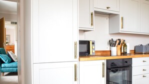 A modern kitchen with white cabinetry, a wooden countertop, a microwave, a toaster, and an oven.