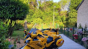 Ein gelbes Motorrad steht auf einem befestigten Weg in einem Garten.