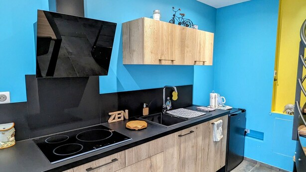 Eine moderne Küche mit einem schwarzen Herd, Holzschränken und einer blauen Wand.