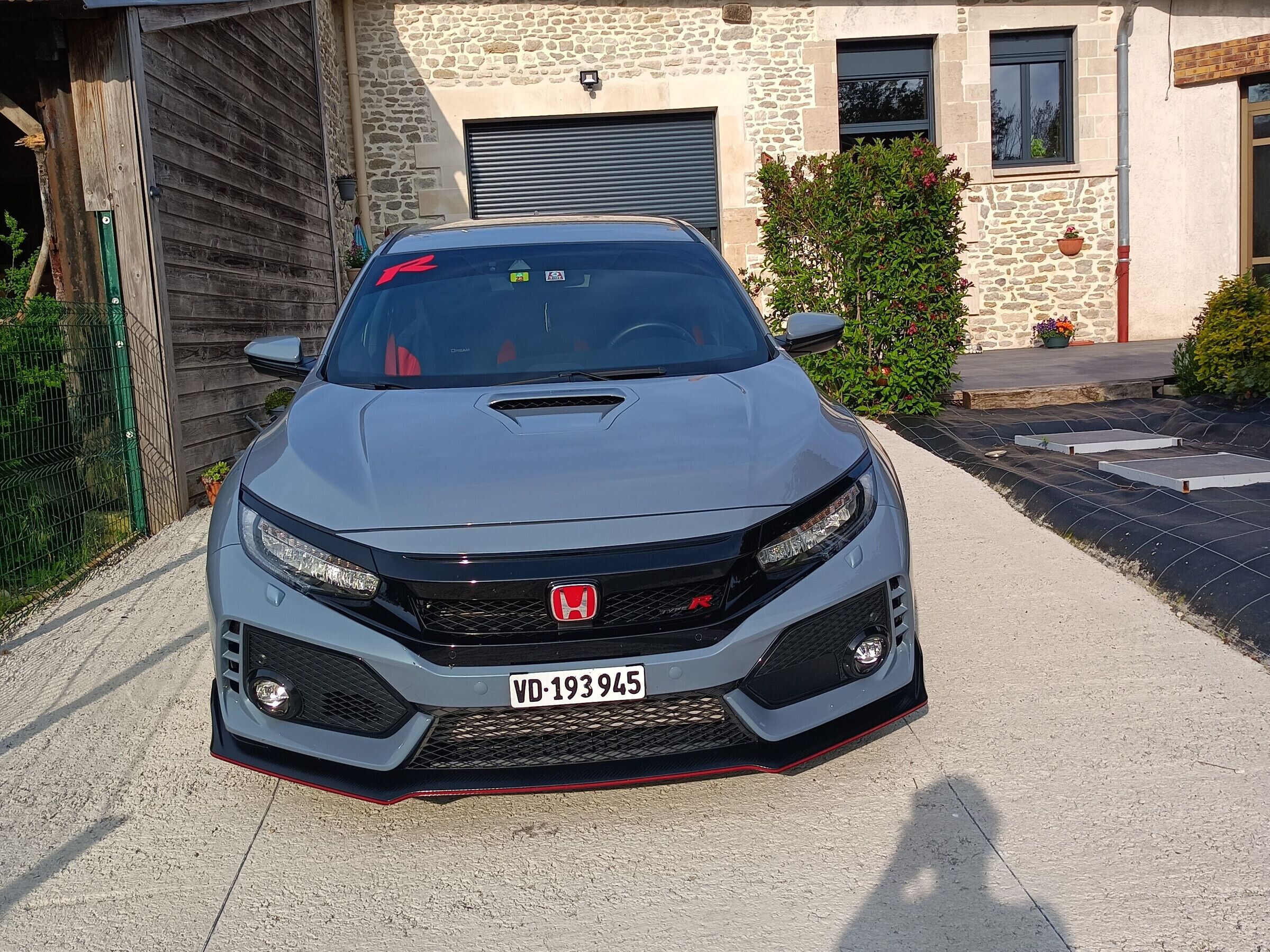 Un Honda CR-V est garé devant un bâtiment en pierre doté d’un garage.
